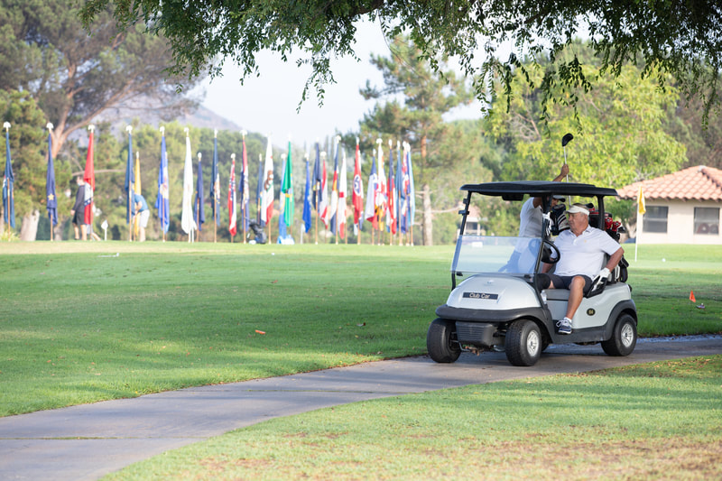 Golf Cart on the course at the Oaks North Golf Club in front of flags during a charity golf tournament by Donna Coleman 
